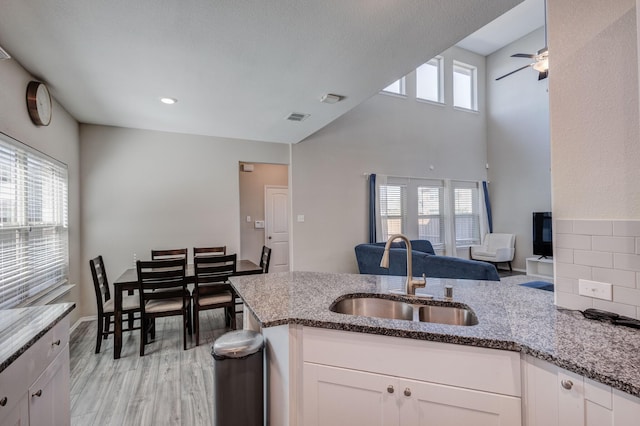 kitchen featuring sink, white cabinetry, light hardwood / wood-style flooring, kitchen peninsula, and stone counters