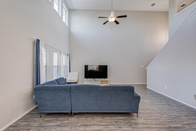 living room featuring wood-type flooring, plenty of natural light, a towering ceiling, and ceiling fan