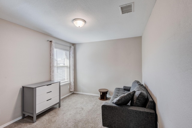 living area featuring light carpet and a textured ceiling