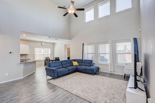 living room featuring sink, light hardwood / wood-style floors, a healthy amount of sunlight, and ceiling fan