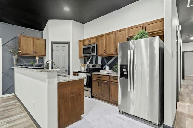 kitchen with appliances with stainless steel finishes, sink, backsplash, and light stone counters