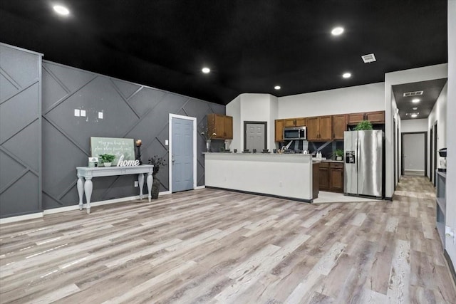 kitchen with appliances with stainless steel finishes and light hardwood / wood-style floors