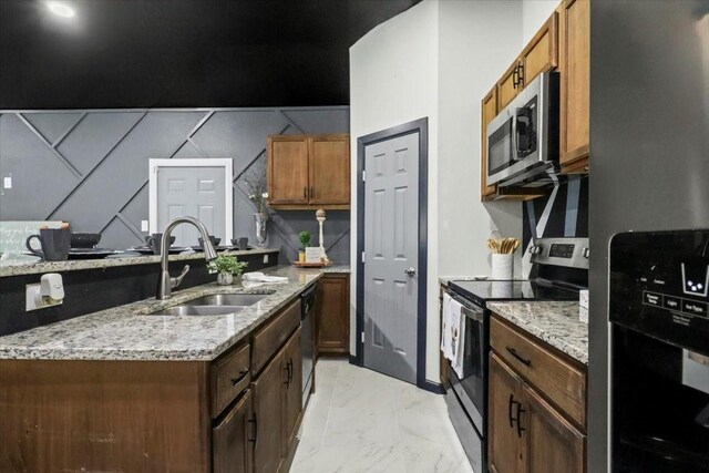 kitchen featuring stainless steel appliances, light stone countertops, sink, and kitchen peninsula