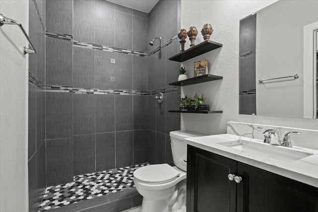 bathroom with vanity, toilet, and tiled shower