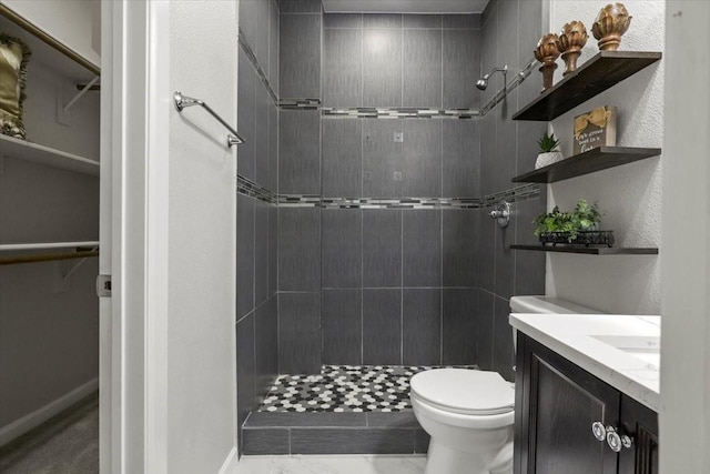 bathroom featuring vanity, toilet, and a tile shower