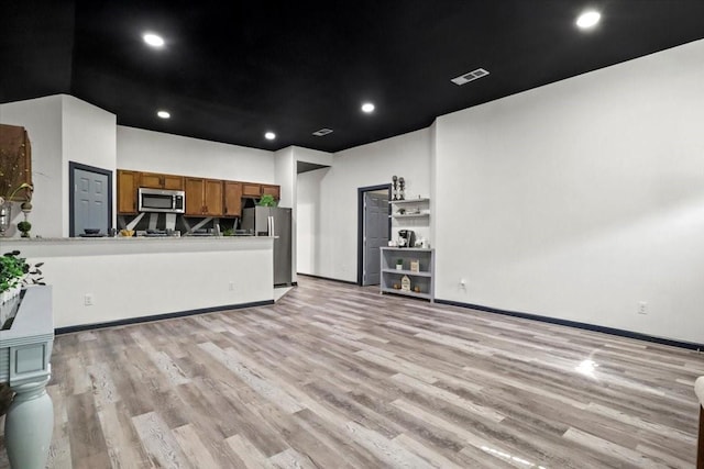 kitchen featuring appliances with stainless steel finishes, kitchen peninsula, and light hardwood / wood-style floors