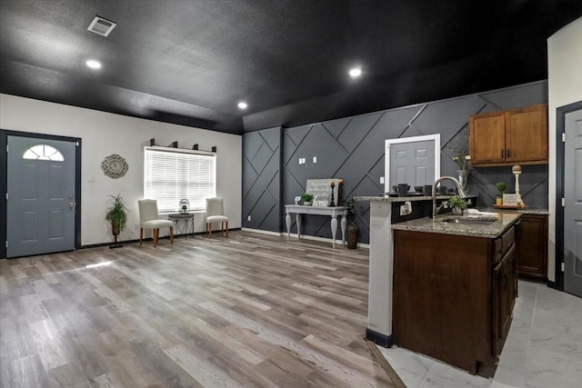 kitchen featuring light stone countertops, sink, a textured ceiling, and light hardwood / wood-style floors