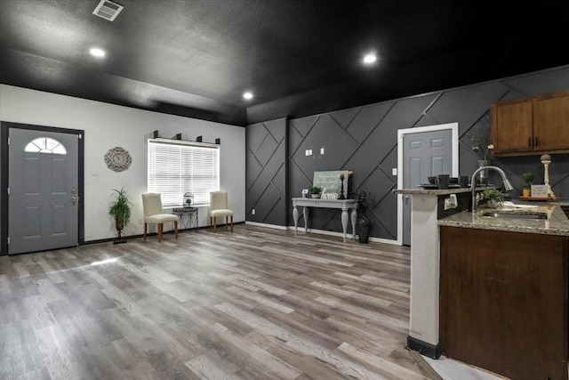 kitchen with light stone counters, sink, a textured ceiling, and light wood-type flooring