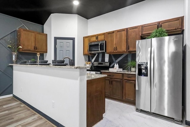 kitchen with light stone counters, appliances with stainless steel finishes, kitchen peninsula, and tasteful backsplash