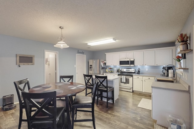 dining space featuring wood-type flooring, sink, and a textured ceiling