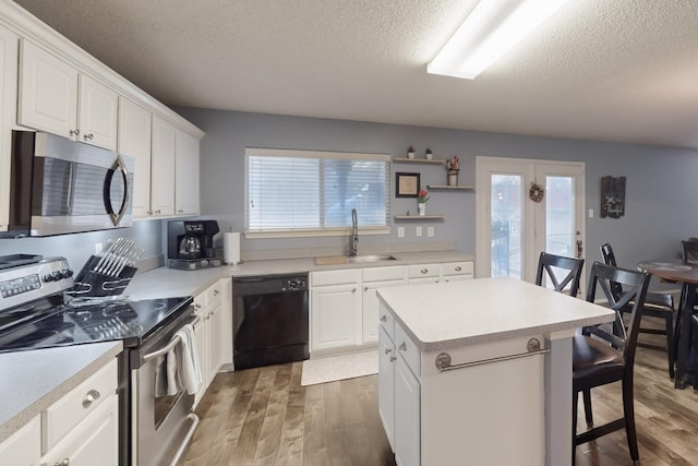 kitchen with sink, a breakfast bar area, appliances with stainless steel finishes, a center island, and white cabinets