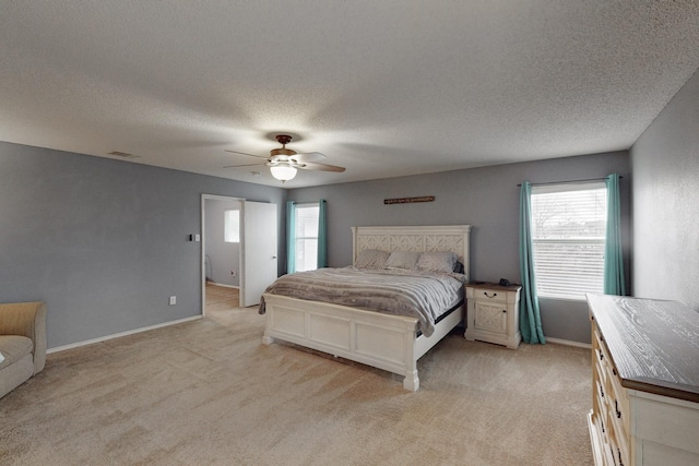 bedroom with ceiling fan, light carpet, and a textured ceiling