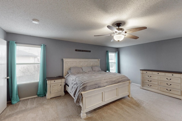 bedroom with a textured ceiling, light colored carpet, and ceiling fan