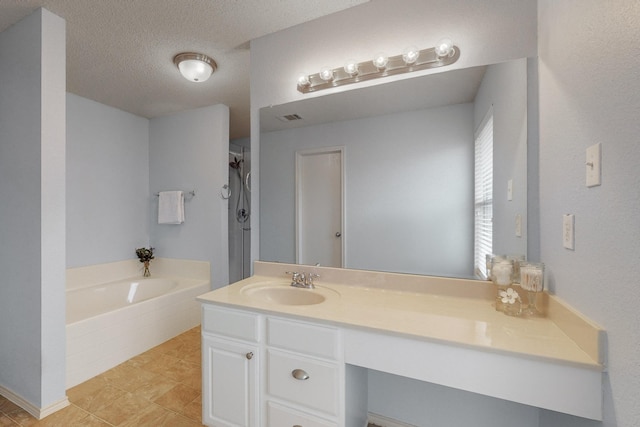 bathroom with tile patterned floors, vanity, a bathtub, and a textured ceiling