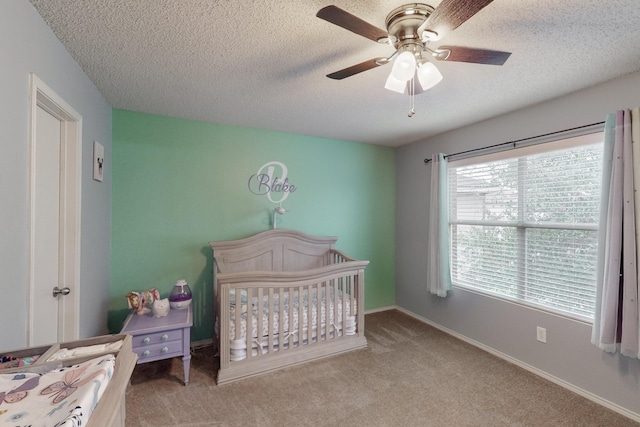 carpeted bedroom featuring a crib, ceiling fan, and a textured ceiling