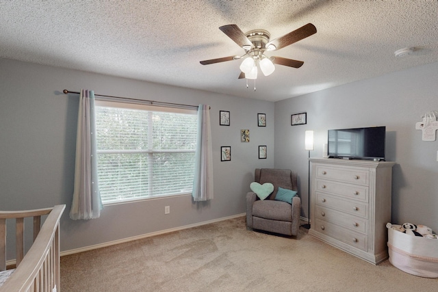 living area with ceiling fan, light colored carpet, and a textured ceiling