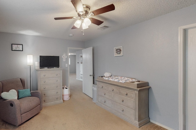 sitting room with ceiling fan, light colored carpet, and a textured ceiling