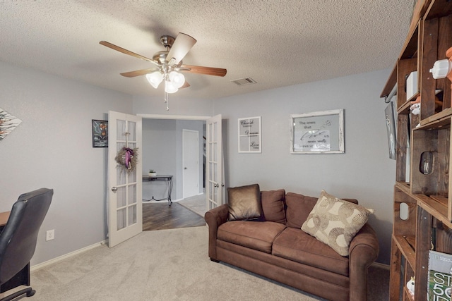 carpeted office space with a textured ceiling, french doors, and ceiling fan