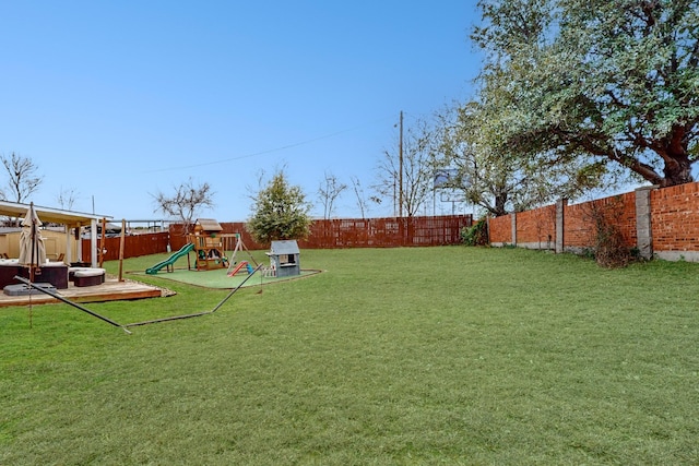 view of yard featuring a playground and a hot tub