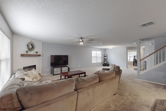 living room with ceiling fan, light colored carpet, and a textured ceiling