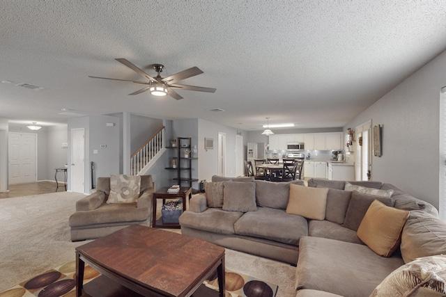 carpeted living room with ceiling fan and a textured ceiling