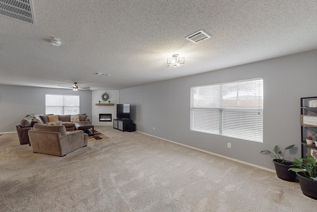 living room with ceiling fan, light colored carpet, and a textured ceiling