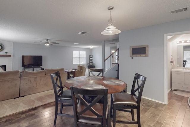 dining area with sink, hardwood / wood-style flooring, a fireplace, and ceiling fan