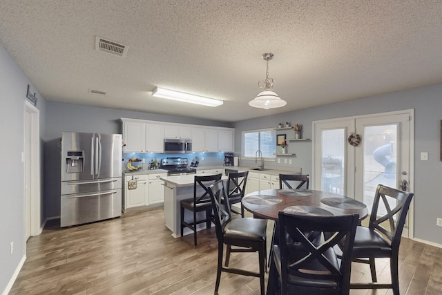 dining space featuring sink, a textured ceiling, and light wood-type flooring