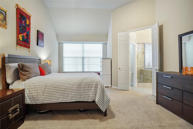 bedroom with ensuite bathroom, vaulted ceiling, and light carpet