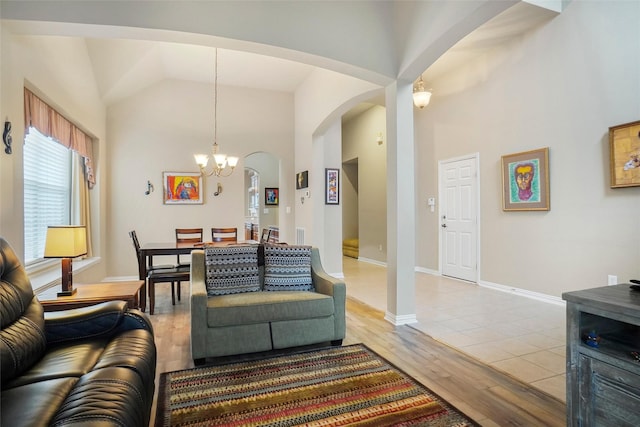 living room with an inviting chandelier, high vaulted ceiling, and light hardwood / wood-style floors