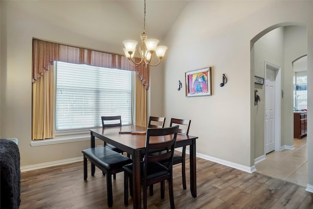 dining space with lofted ceiling, hardwood / wood-style floors, and an inviting chandelier