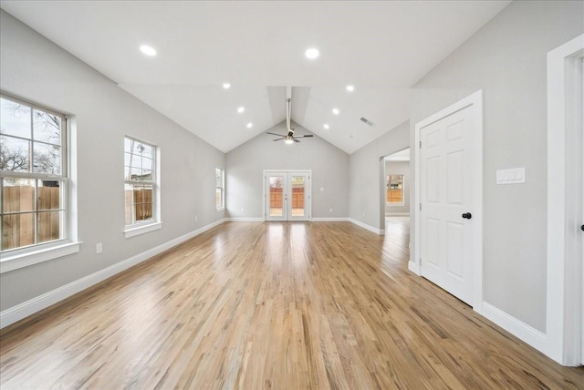 unfurnished living room featuring french doors, plenty of natural light, lofted ceiling, and light hardwood / wood-style flooring