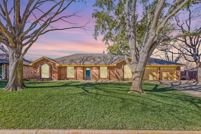 single story home featuring a garage and a lawn