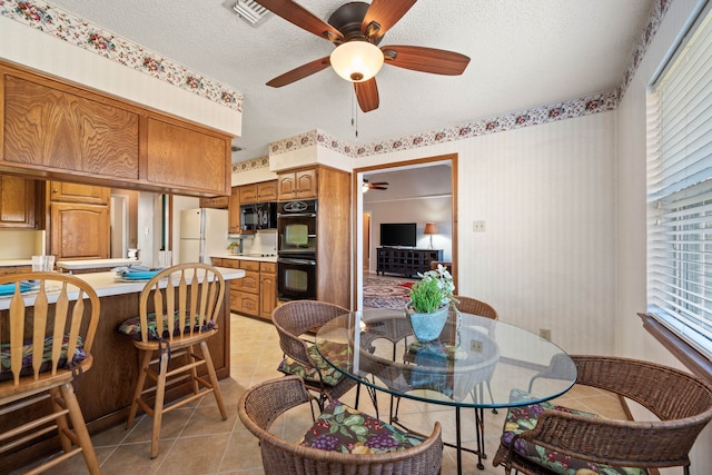 dining area featuring ceiling fan, a textured ceiling, and light tile patterned flooring