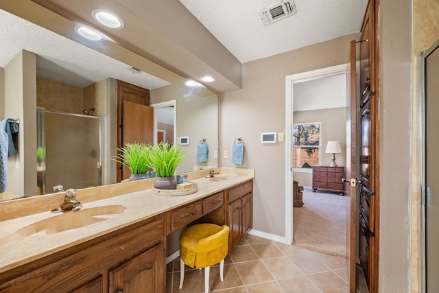 bathroom with tile patterned flooring, vanity, a textured ceiling, and a shower with shower door