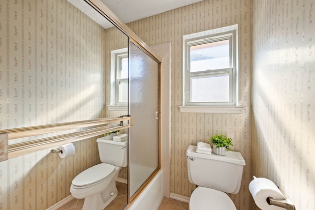 bathroom with tile patterned flooring, a textured ceiling, bath / shower combo with glass door, and toilet