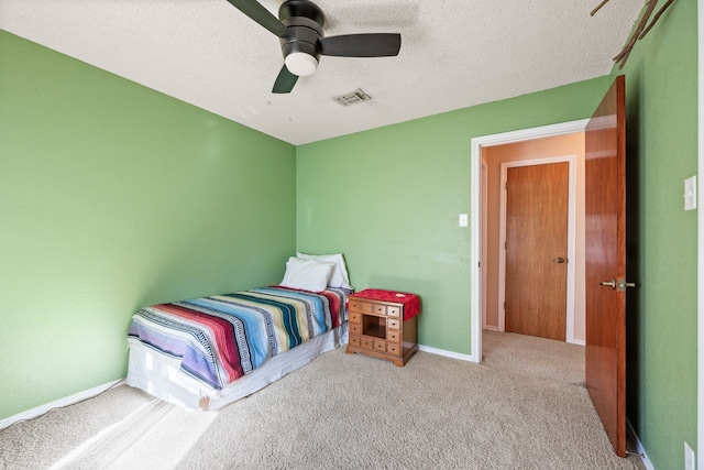 carpeted bedroom featuring ceiling fan and a textured ceiling