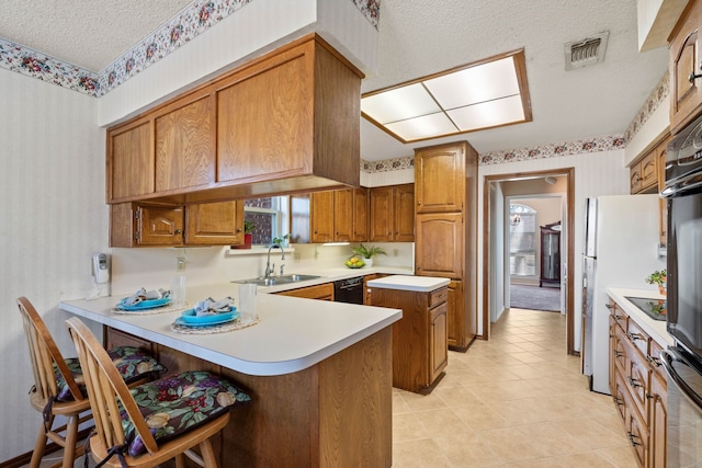 kitchen with a breakfast bar, sink, a textured ceiling, dishwasher, and kitchen peninsula