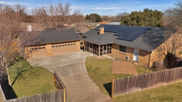 view of front of home featuring a front lawn, a garage, a sunroom, and solar panels