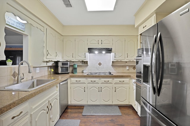 kitchen featuring sink, backsplash, a skylight, stainless steel appliances, and dark hardwood / wood-style flooring