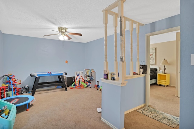 playroom featuring ceiling fan, carpet, and a textured ceiling