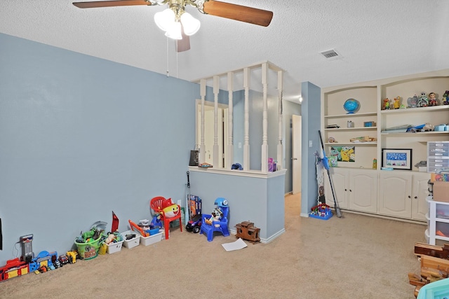 recreation room with ceiling fan, carpet, and a textured ceiling