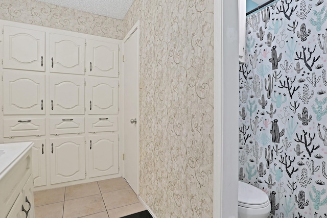 bathroom featuring tile patterned floors, toilet, a shower with curtain, a textured ceiling, and vanity