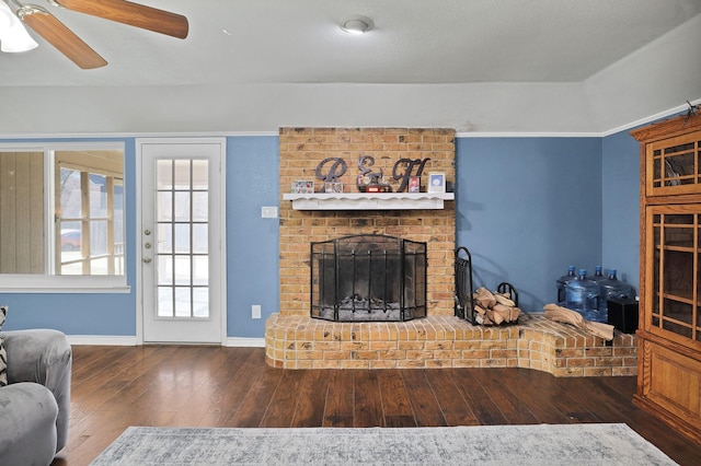 living room with a brick fireplace, dark hardwood / wood-style floors, and ceiling fan