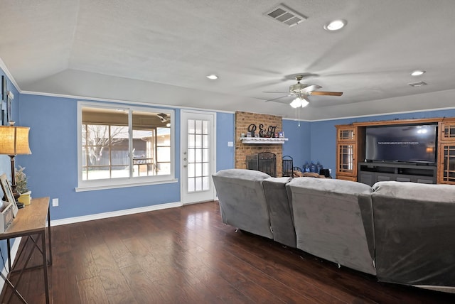 living room with vaulted ceiling, a brick fireplace, a textured ceiling, dark hardwood / wood-style floors, and ceiling fan