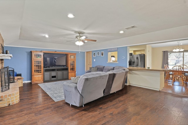 living room featuring a fireplace, dark hardwood / wood-style floors, and ceiling fan with notable chandelier