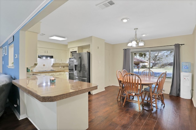 kitchen featuring stainless steel refrigerator with ice dispenser, dark hardwood / wood-style floors, kitchen peninsula, a notable chandelier, and backsplash