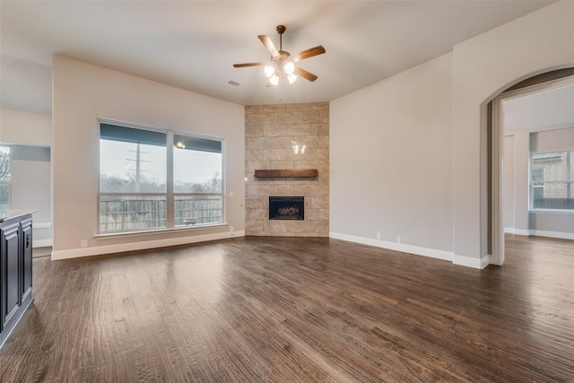 unfurnished living room featuring a wealth of natural light, a fireplace, dark hardwood / wood-style floors, and ceiling fan