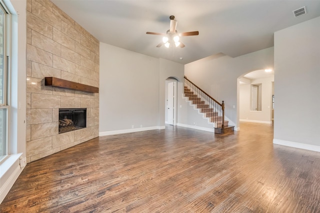 unfurnished living room featuring ceiling fan, dark hardwood / wood-style floors, and a tile fireplace