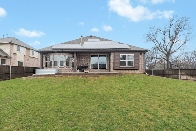 back of house featuring a yard and solar panels